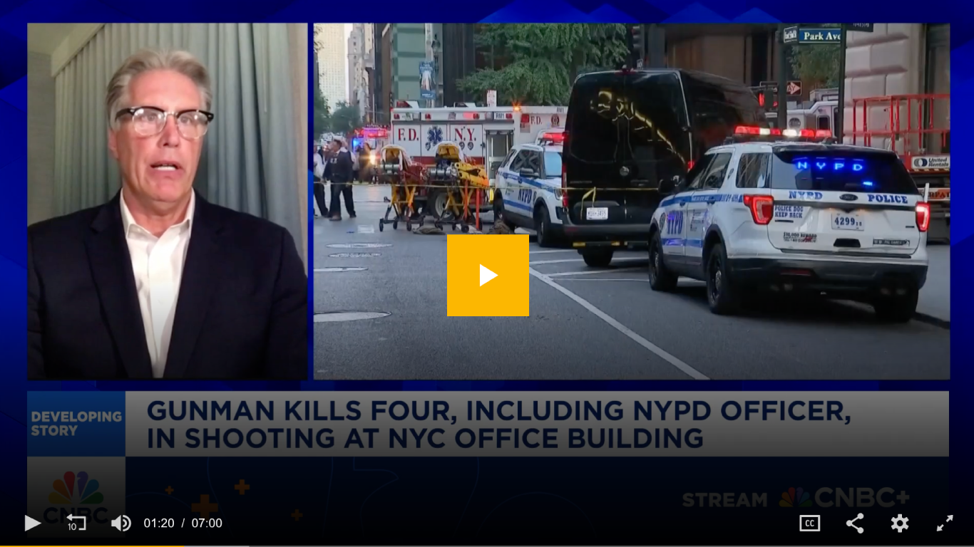 Screenshot from CNBC showing Dave Komendat speaking remotely during a segment on a developing story about a New York City office building shooting. The right side of the screen displays emergency response vehicles, including NYPD police cars and FDNY ambulances, at the scene. Headline text reads: 'Gunman kills four, including NYPD officer, in shooting at NYC office building.