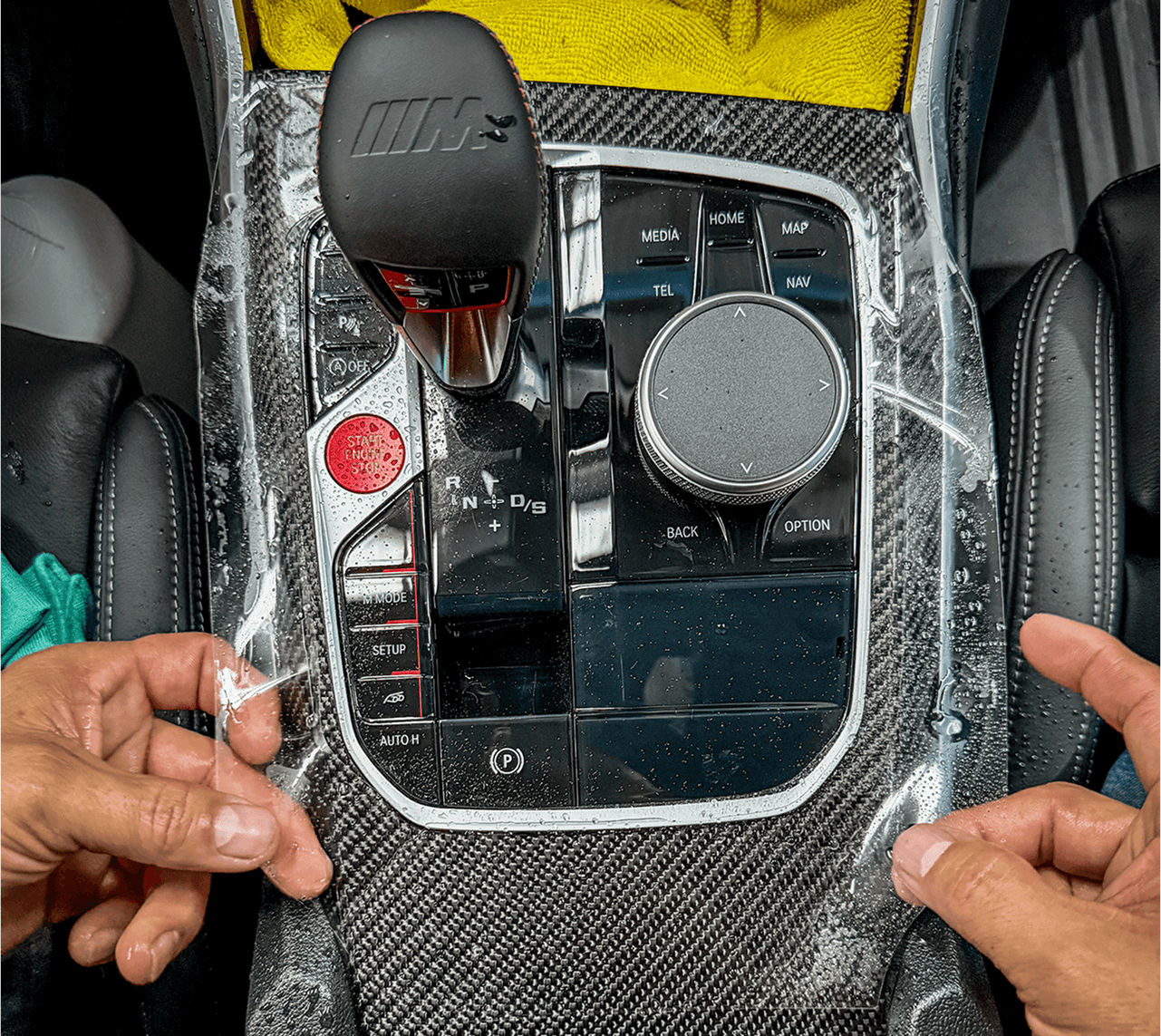 Aplicación de PPF en consola negra piano para proteger interior de auto nuevo