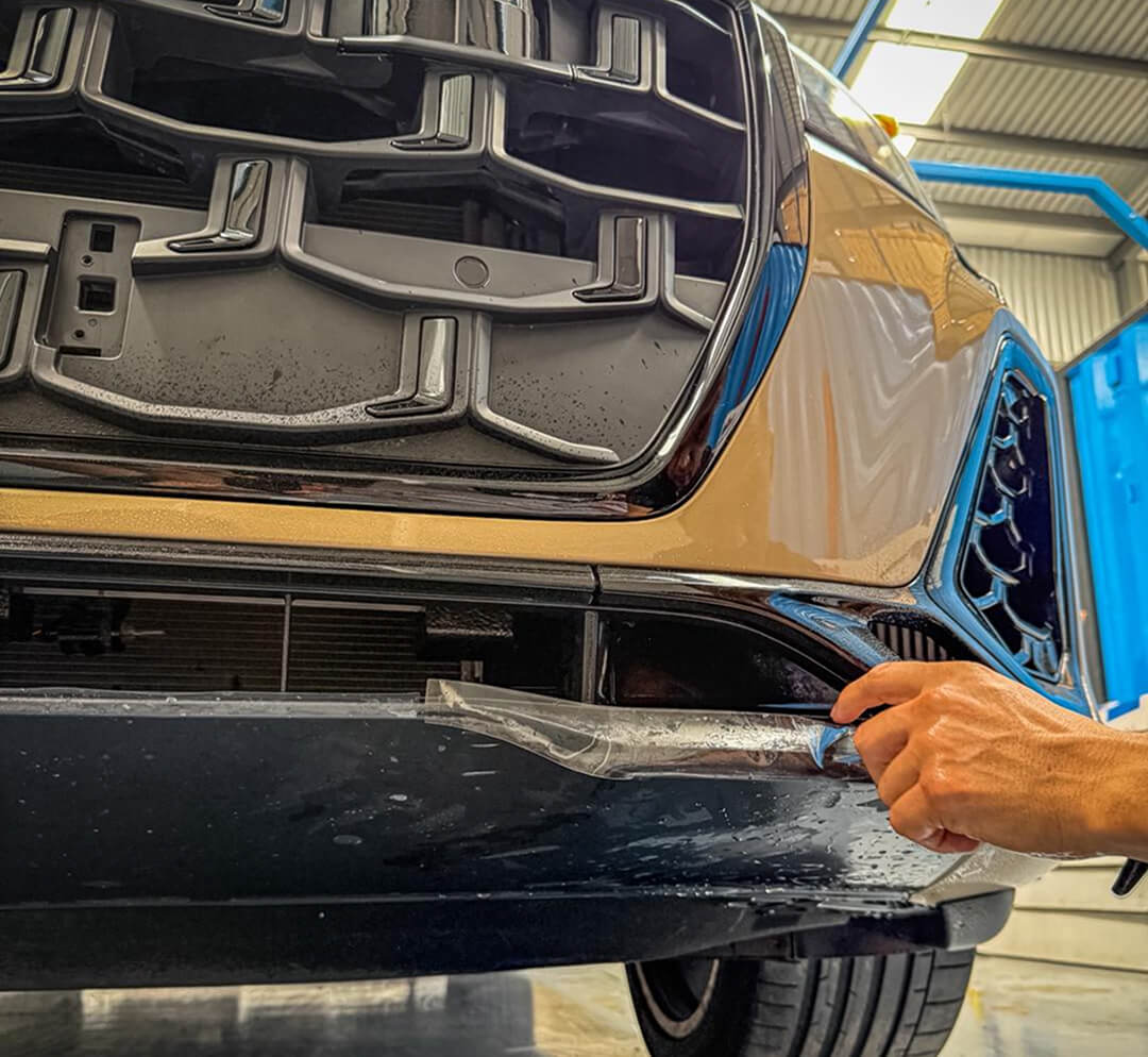 Técnico aplicando ppf para autos en fascia delantera de SUV Audi en Querétaro; protección contra impactos de gravilla y rayones.
