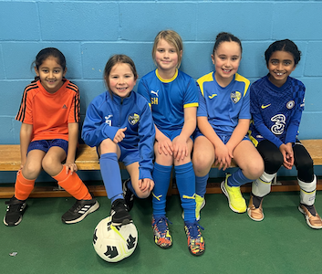 girls sitting on a bench with a soccer ball