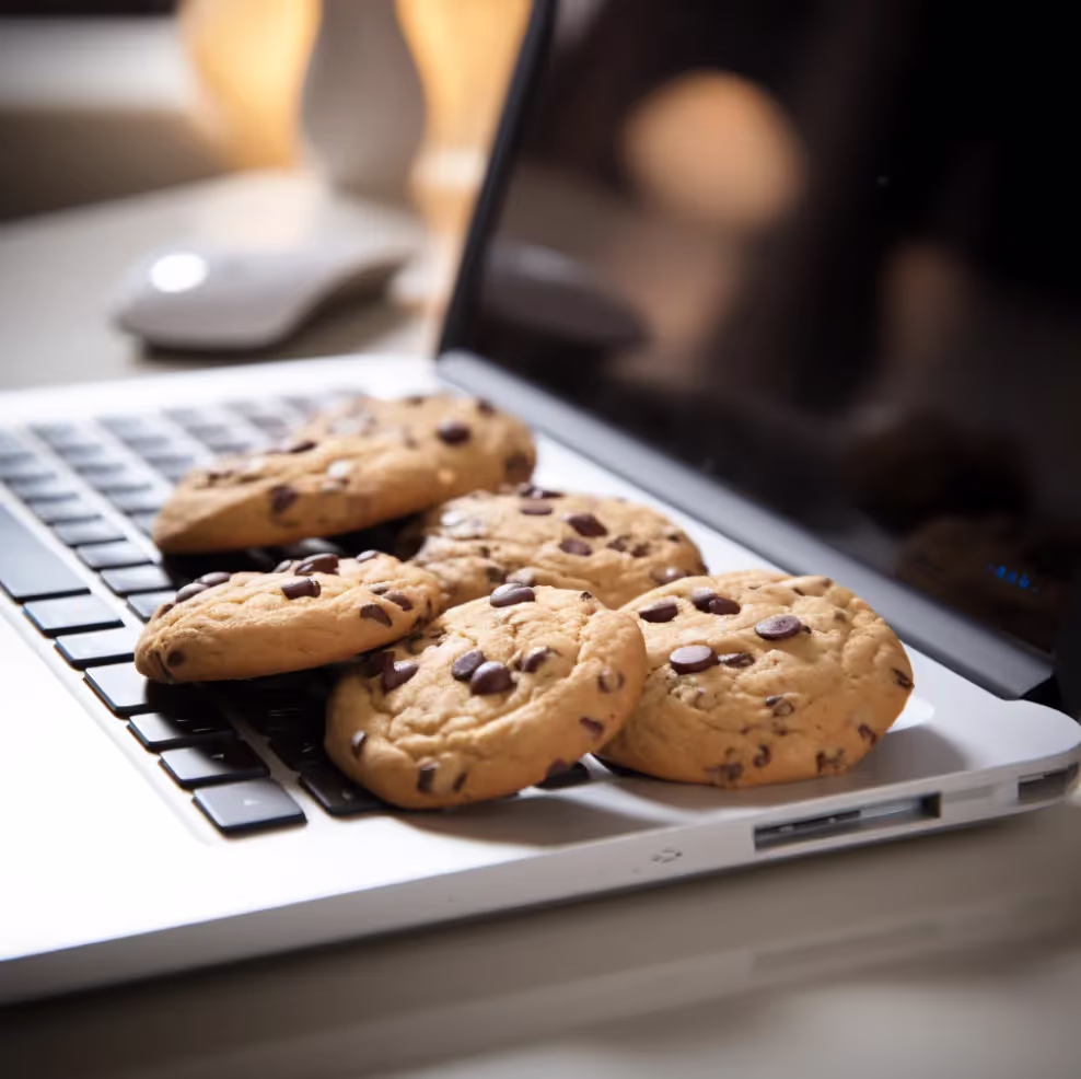 Photograph of chocolate chip cookies on a silver laptop keyboard