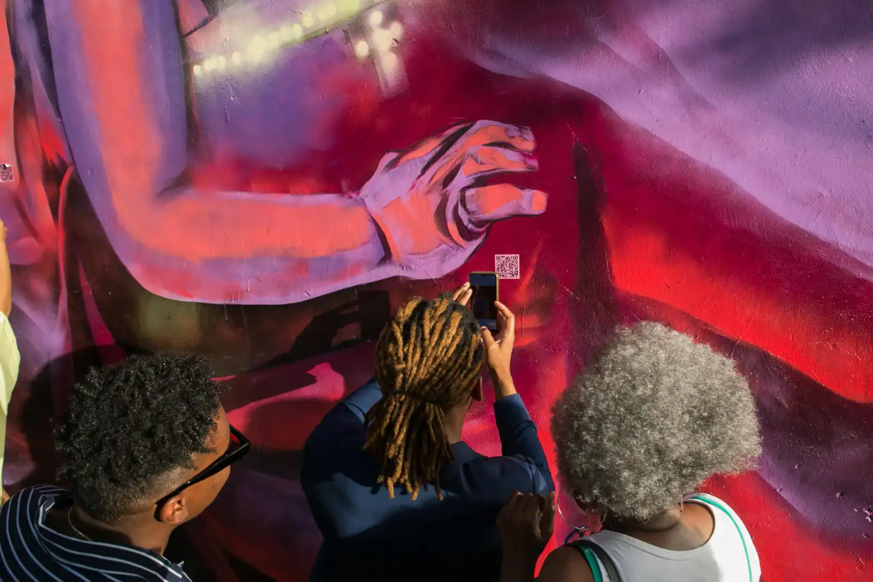Individuals scanning a QR code on a vivid wall mural.