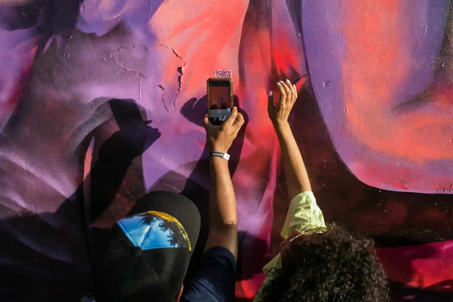 Two people interacting with a QR code on a mural.