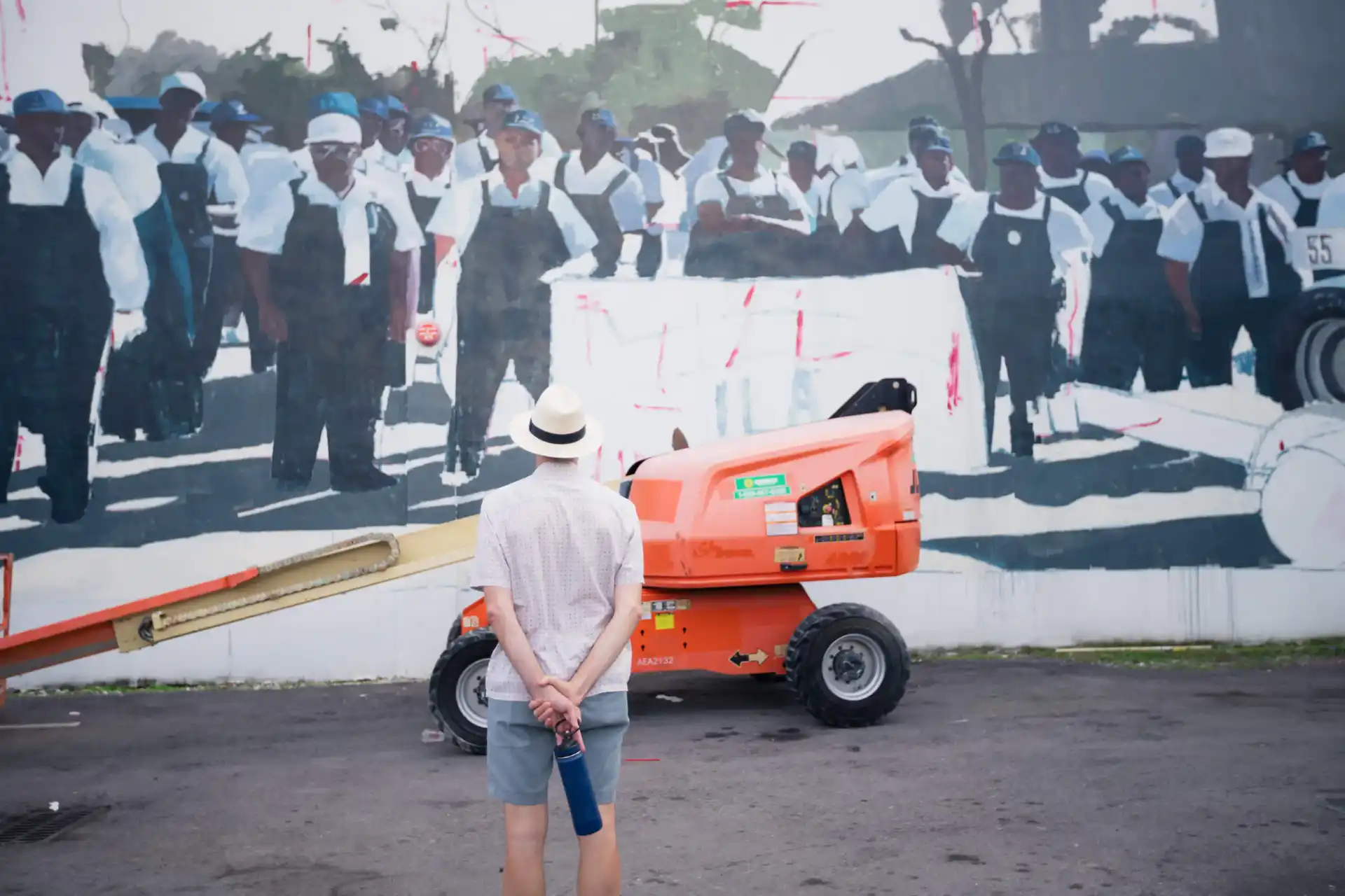 A person observing a longshoremen mural with lift equipment.