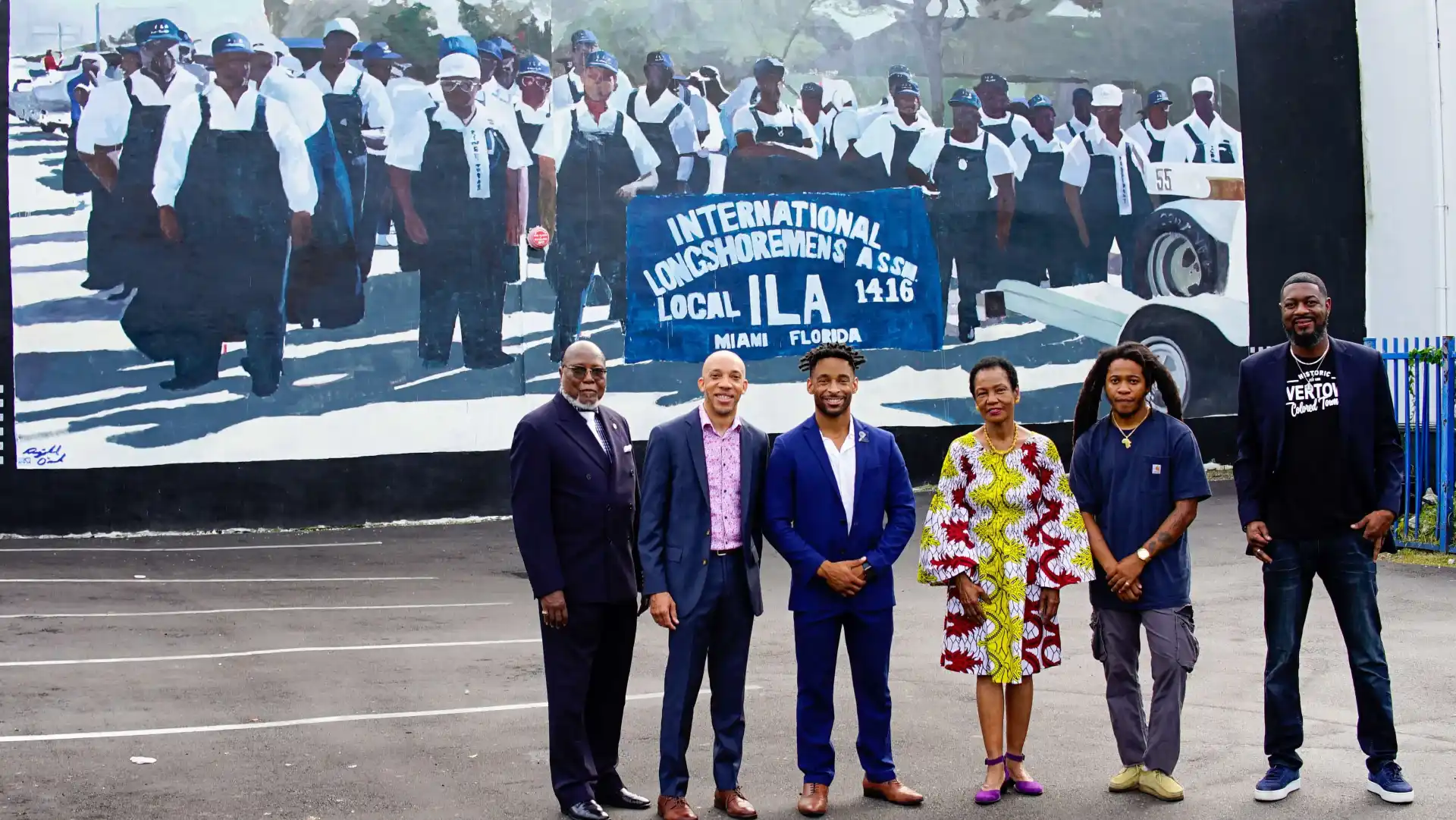 Group of people in front of a mural depicting longshoremen.