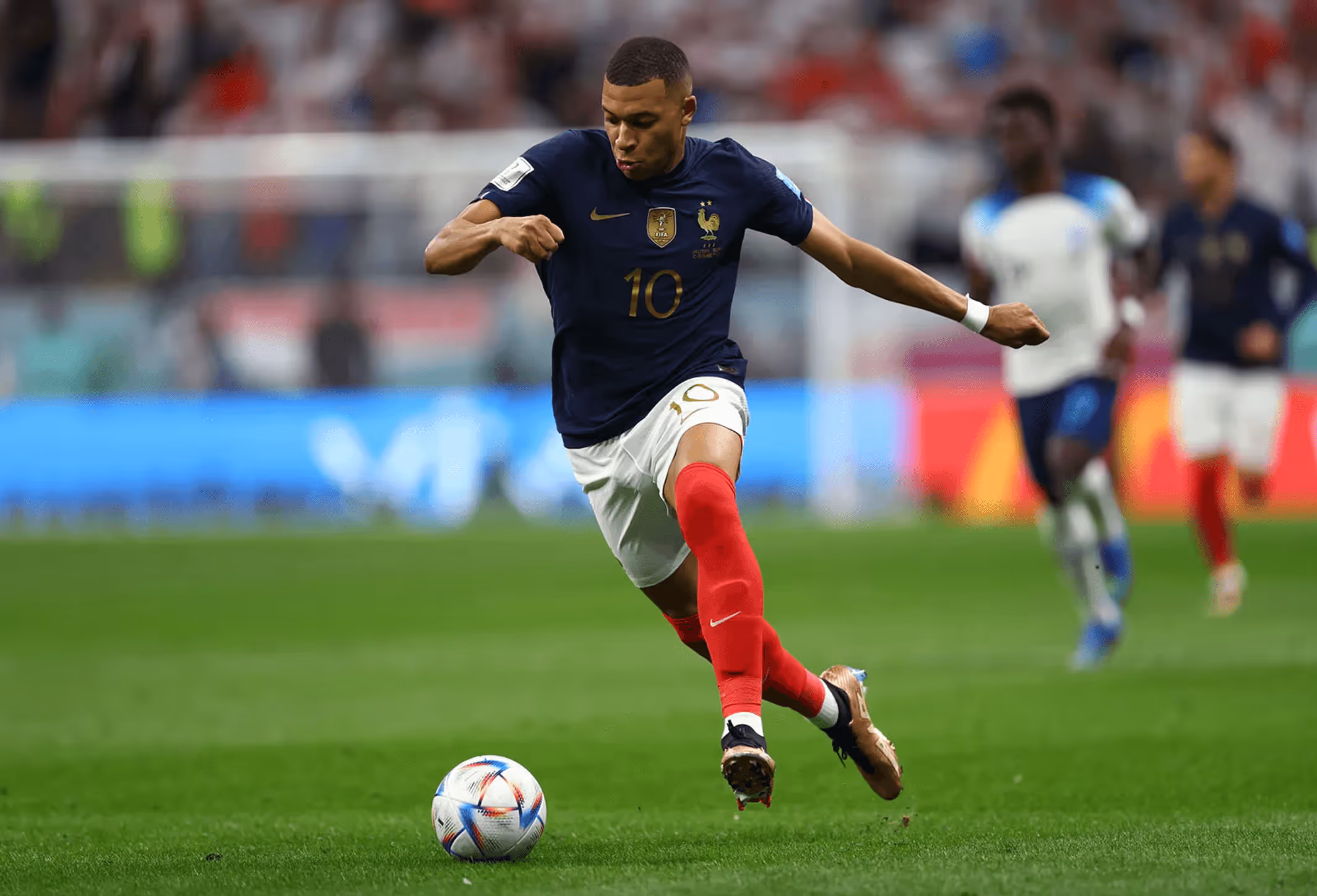 Soccer player in blue jersey with number 10 kicking a ball on a green field.