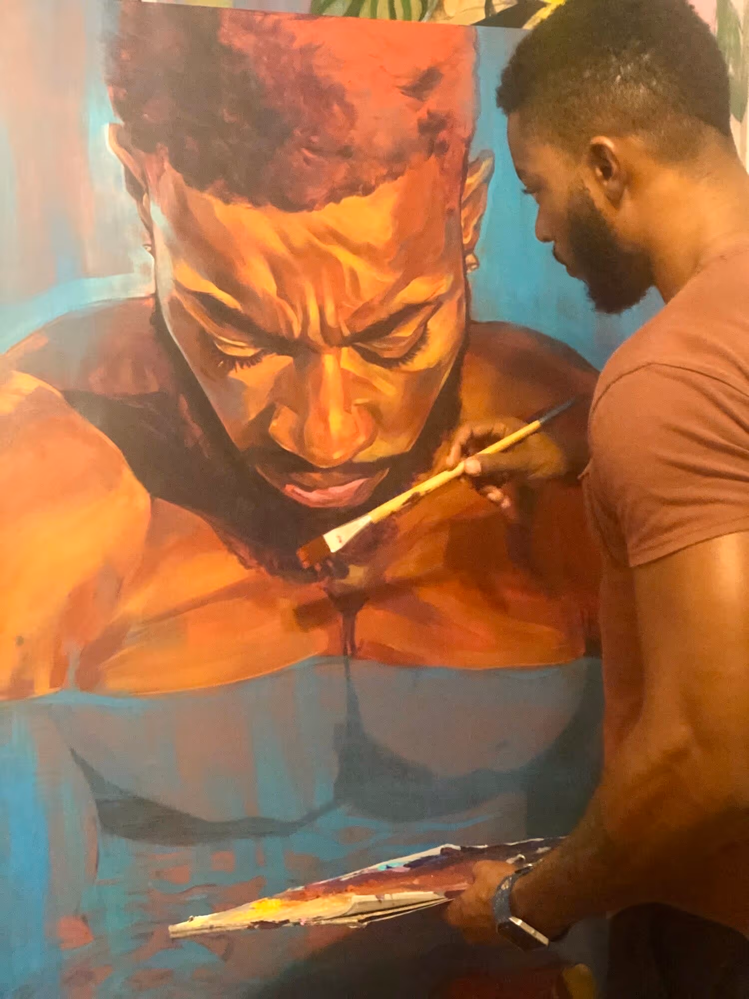 Artist painting a large, detailed portrait of a man's face and upper torso in warm tones on a vertical canvas.