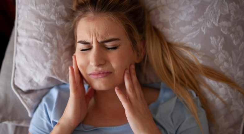 A woman is sleeping uncomfortably because of aligner pain