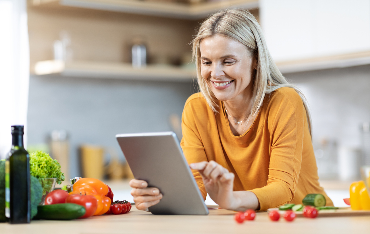 Woman reviewing content calmly on a tablet at a kitchen table