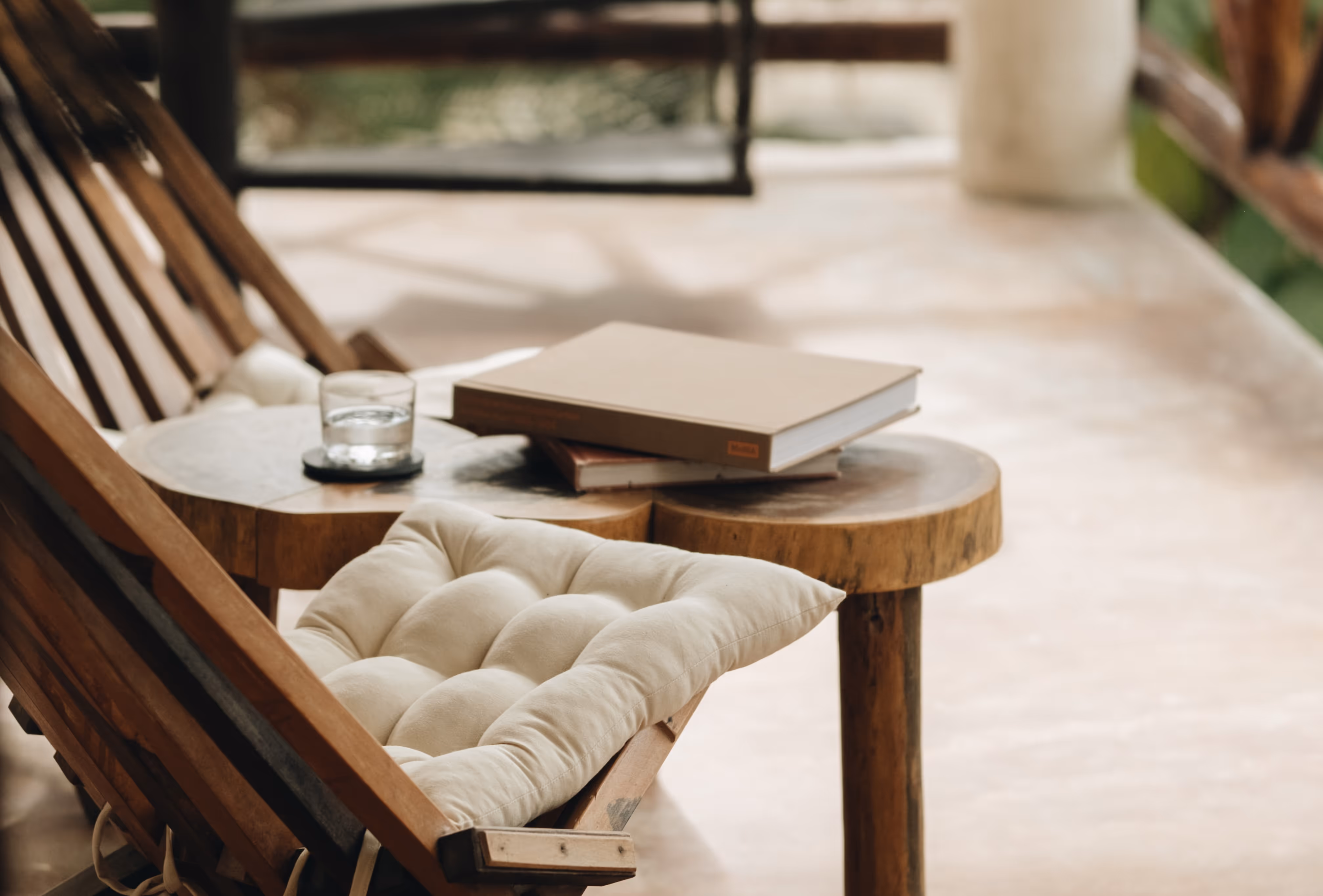 Modern natural wood armchairs from side with coffee table, books on it, and a glass of water.