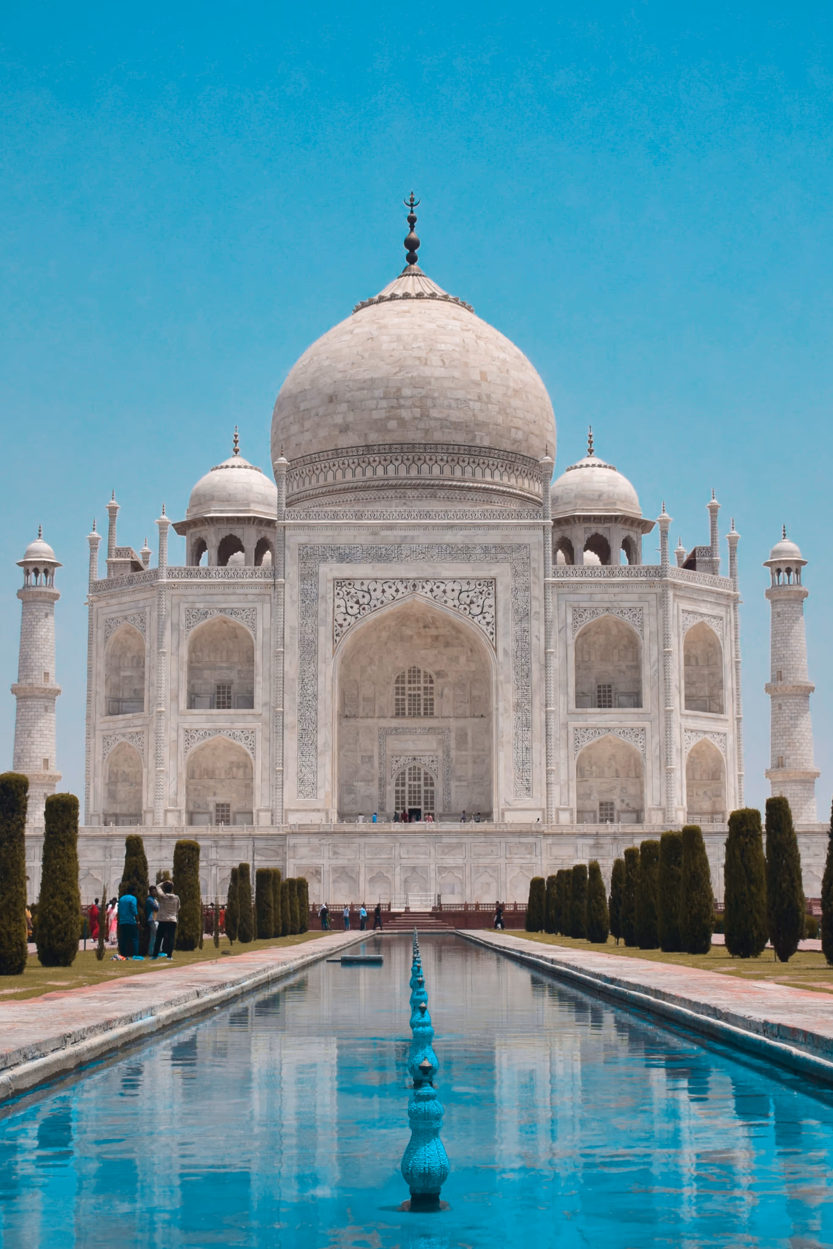 Taj Mahal temple during day time in symmetrical perspective from the water pool.
