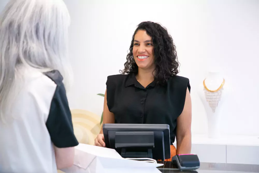 Caissière de magasin heureuse et positive, parlant au client et riant à la caisse