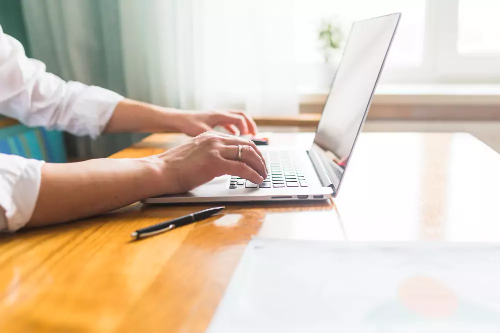 Main de femme d'affaires utilisant un ordinateur portable sur un bureau en bois