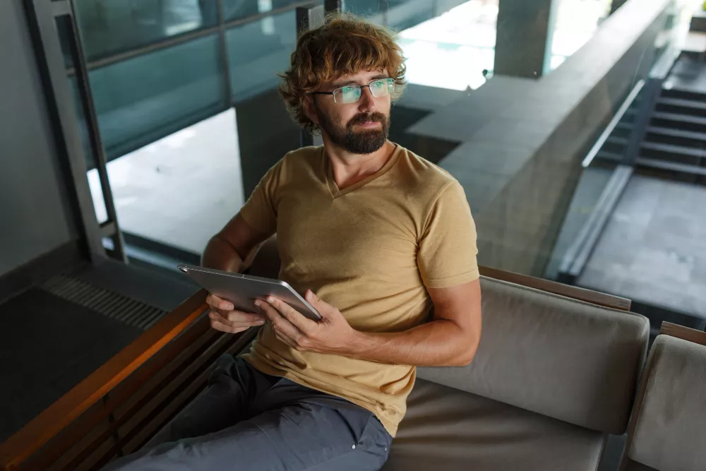 Homme barbu utilisant une tablette dans un immeuble moderne