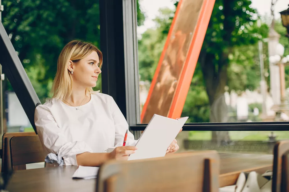 Une femme est assise dans un café avec une lettre