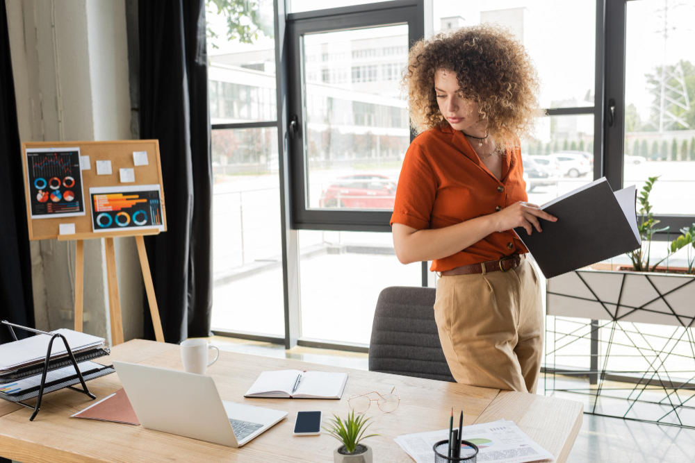 Femme d’affaires aux cheveux bouclés avec un dossier au bureau