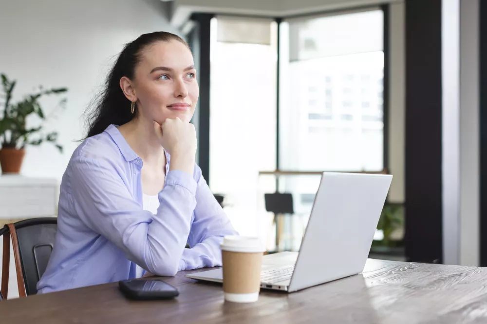 Jeune femme au bureau avec ordinateur portable et café