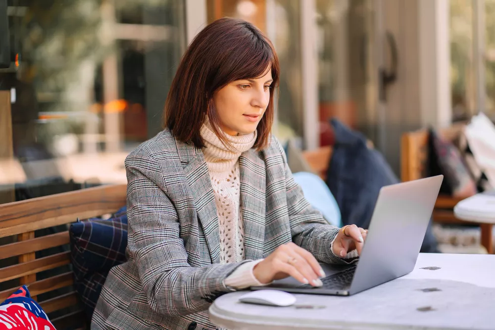 Femme vêtue d’un pull chaud et d’un blazer, travaillant sur un ordinateur portable