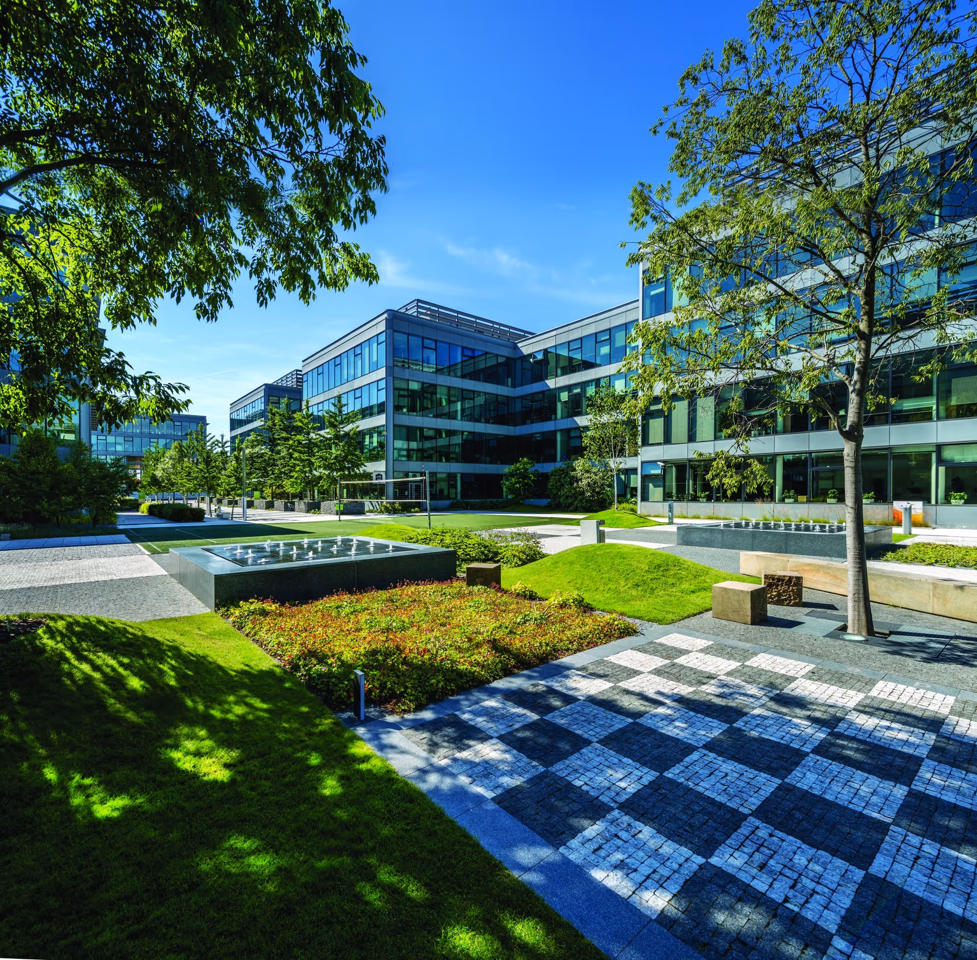 Modern two-story office building with large reflective glass windows and a grassy lawn in front.