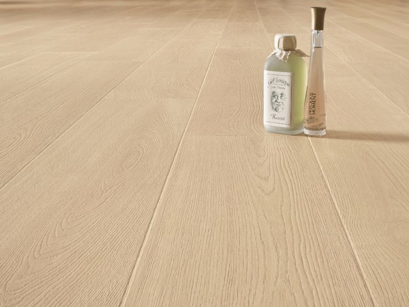 Moderner Innenraum mit Terrazzo-Bodenfliesen, Holzschrank, Rattanstuhl und kleinem weißen Beistelltisch mit Glasflasche und Glas.