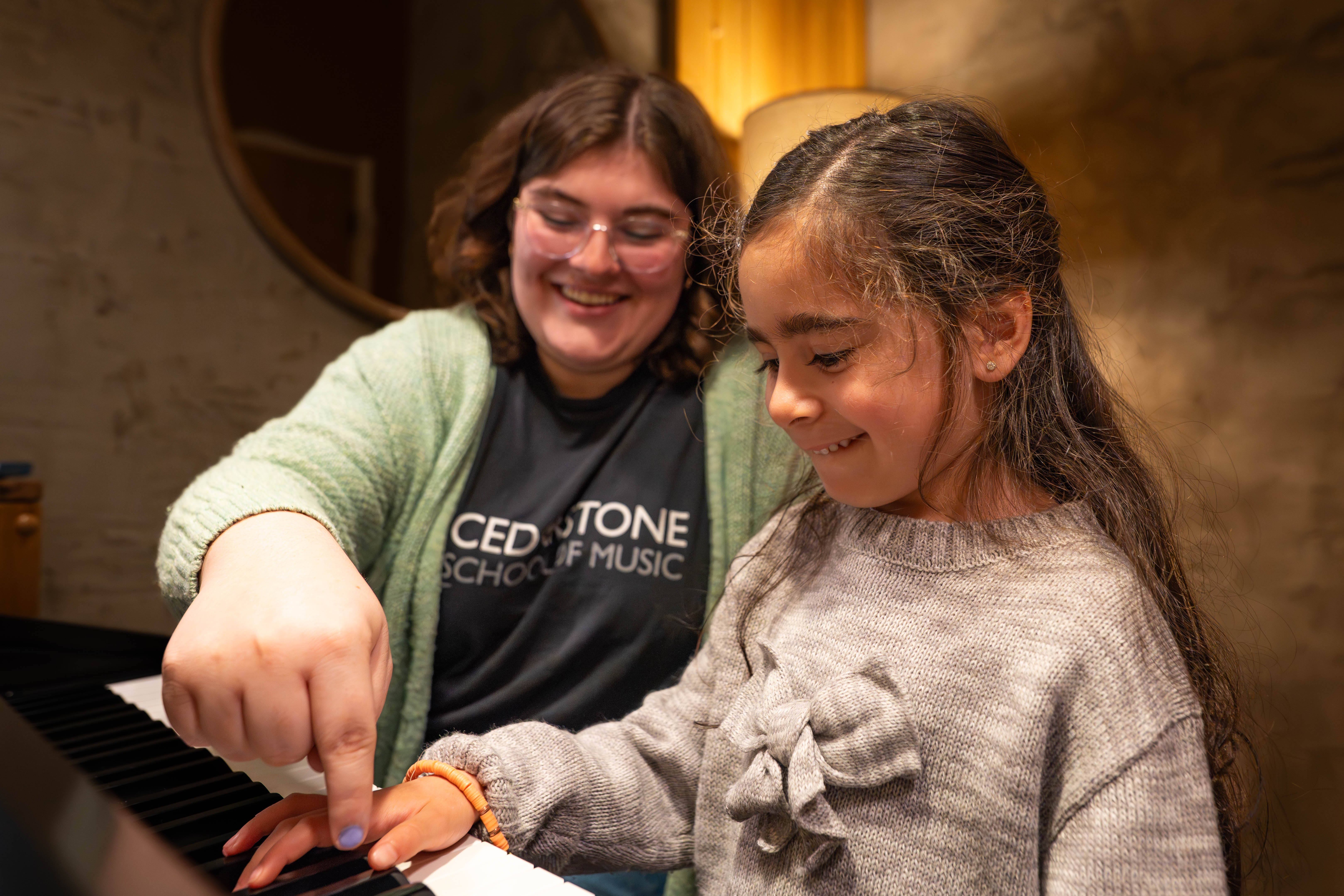 A Cedarstone instructor and young student laughing together during a piano lesson