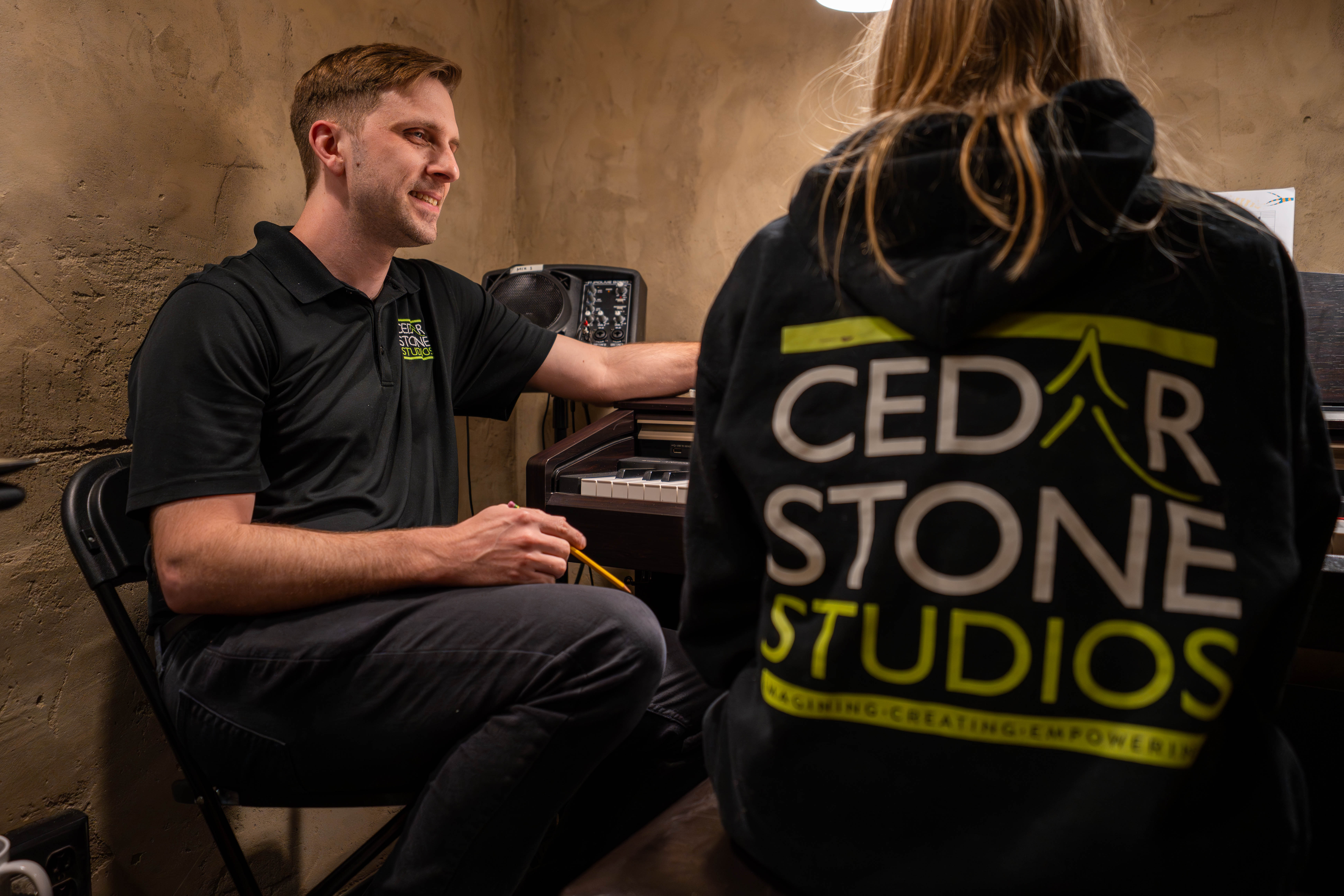 A Cedarstone instructor talking with a student wearing a Cedarstone Studios hoodie