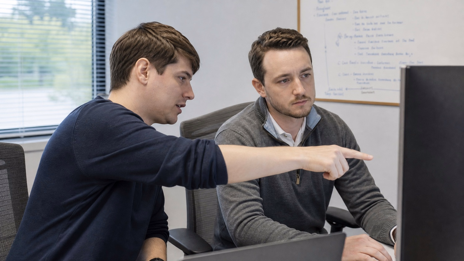 SIDE-BY-SIDE PAIR An IT professional  two people seated side by side reviewin