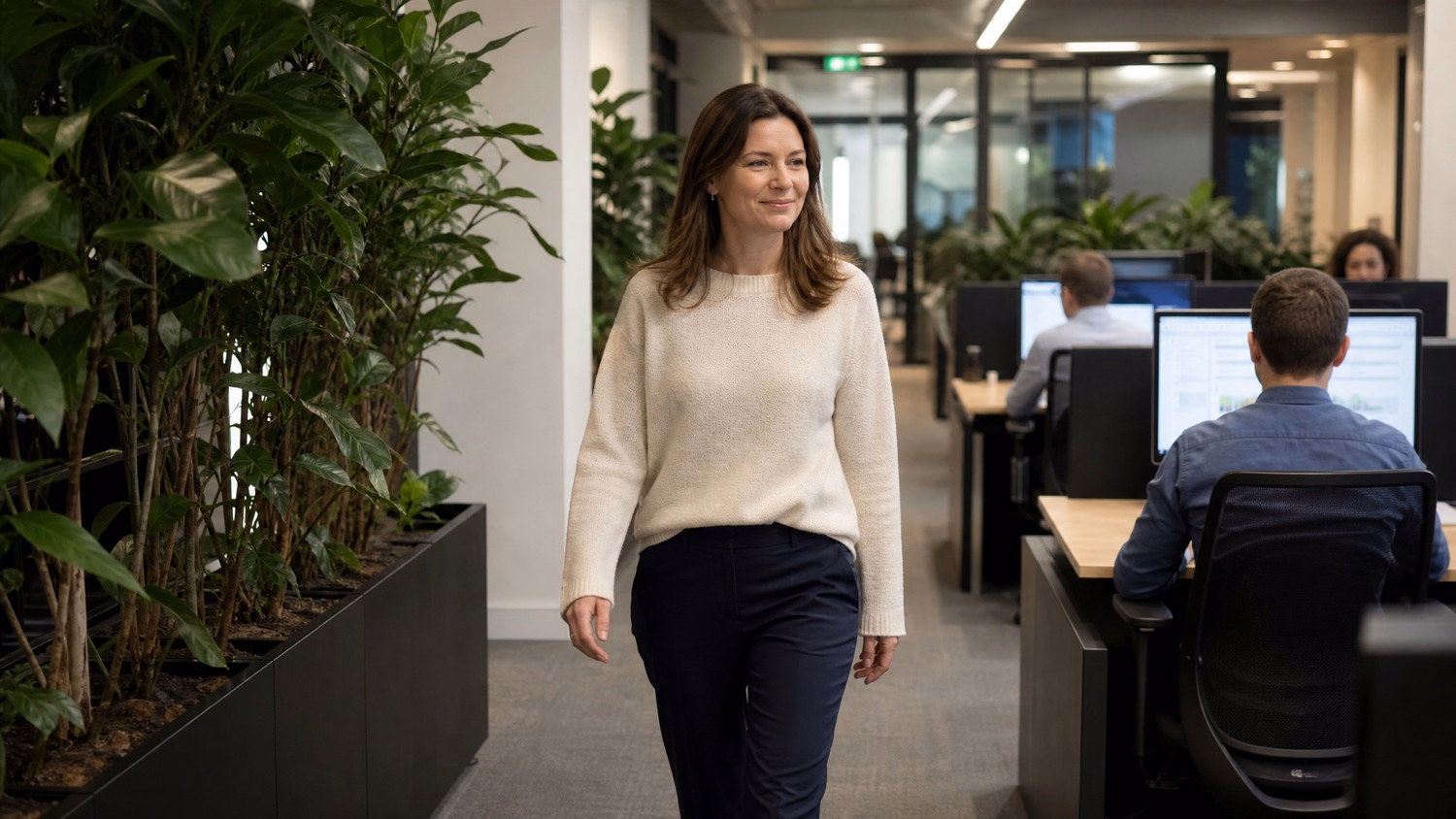 Woman walks down plant-lined office corridor 47