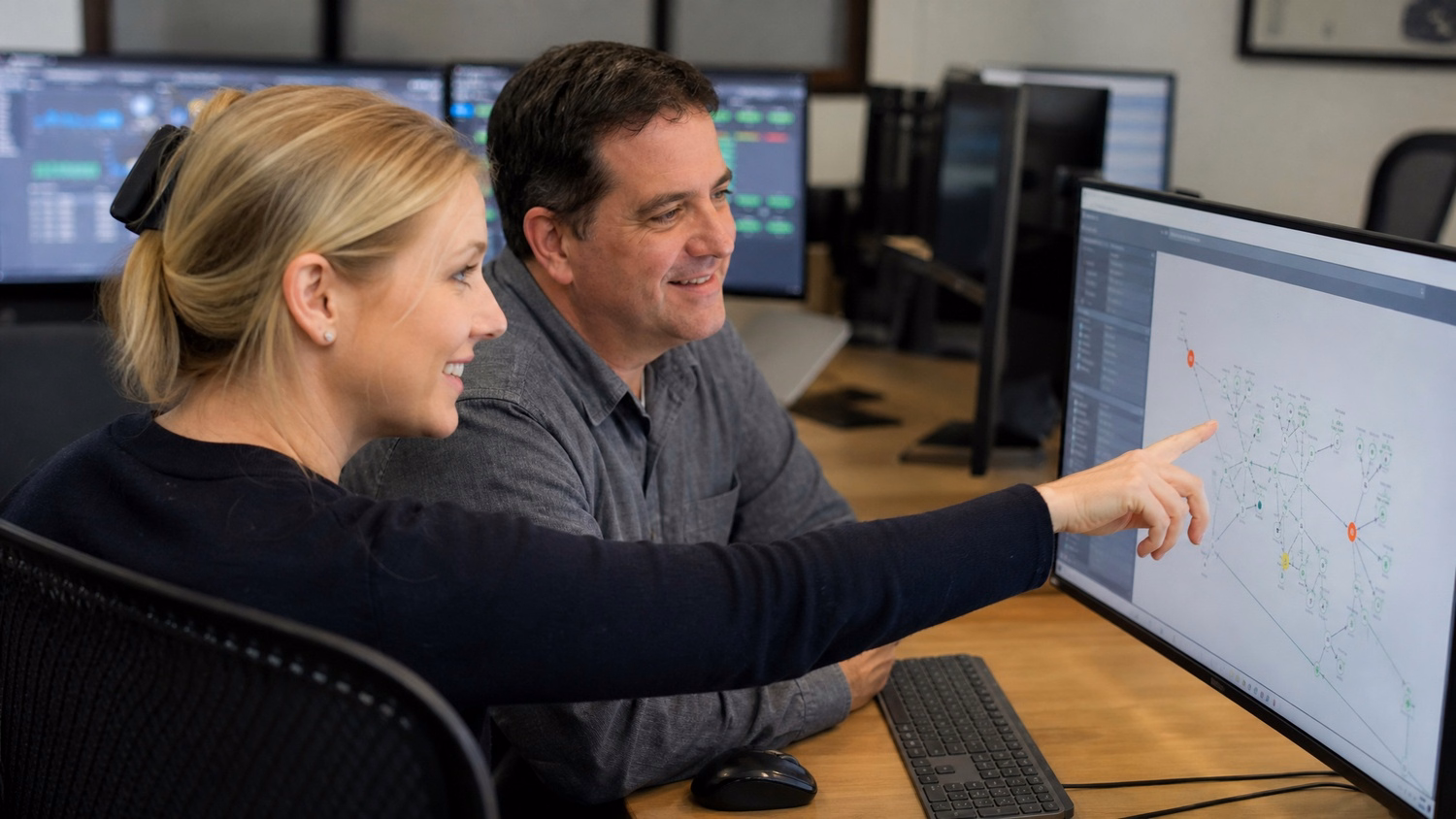 Woman points at network map on shared monitor screen
