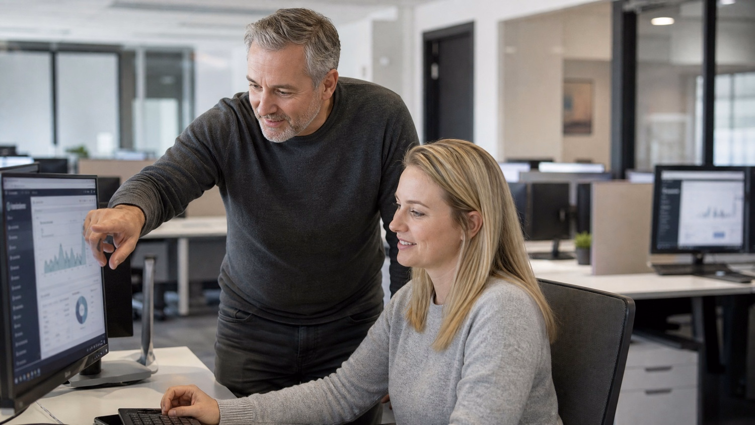 IT manager points at monitor, colleague watches attentively