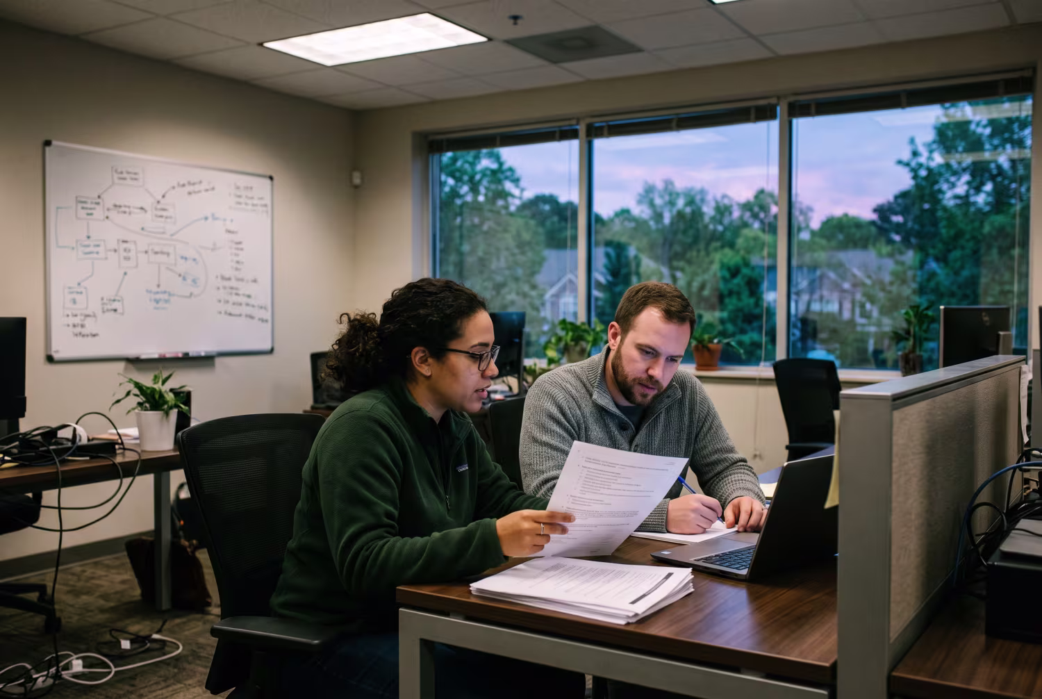 Two IT professionals reviewing cybersecurity training documents in office