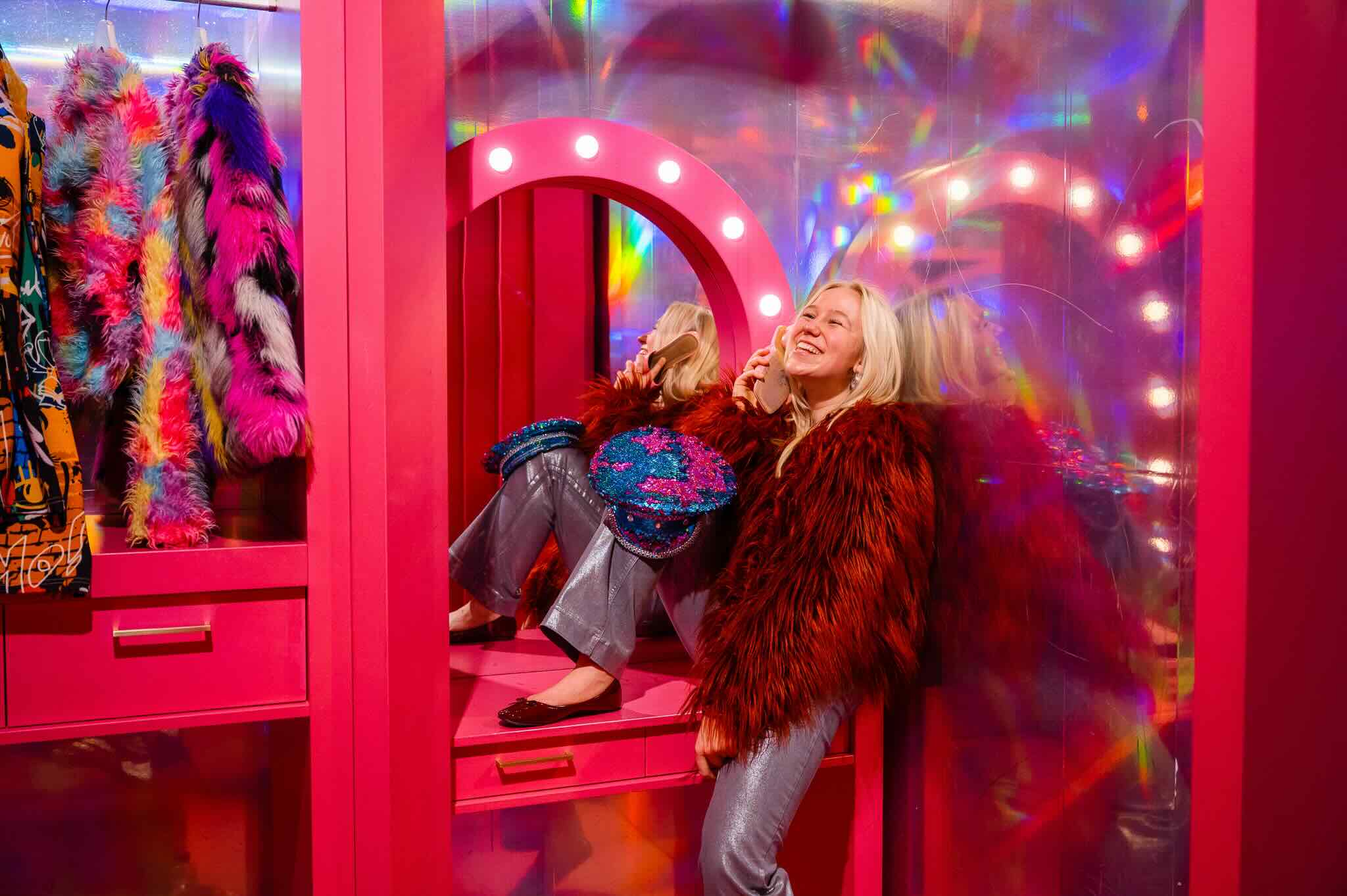 Two visitors posing in a pink neon room
