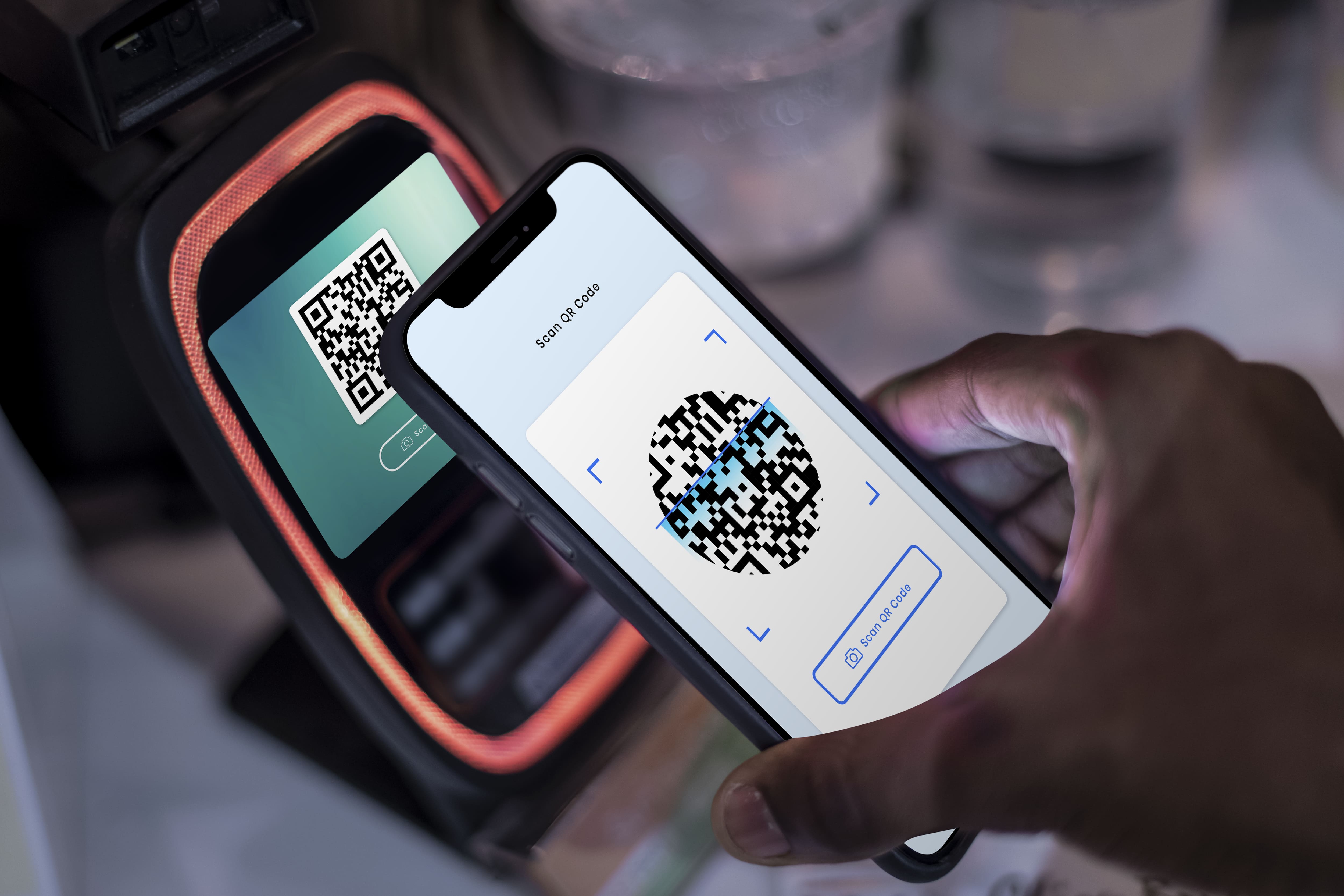 mão segurando um smartphone para escanear um QR Code de pagamento por aproximação