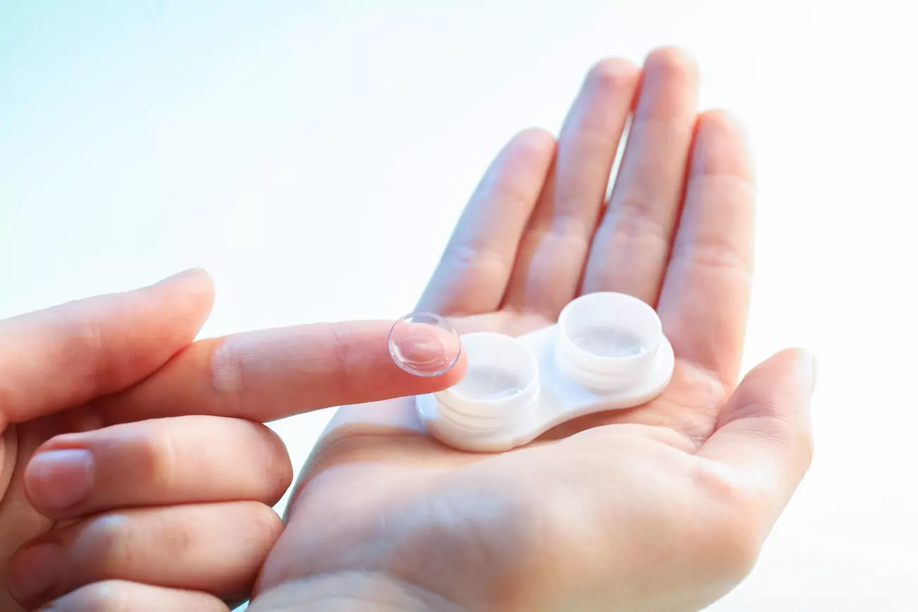 Woman holding a contact lens in her hand. 