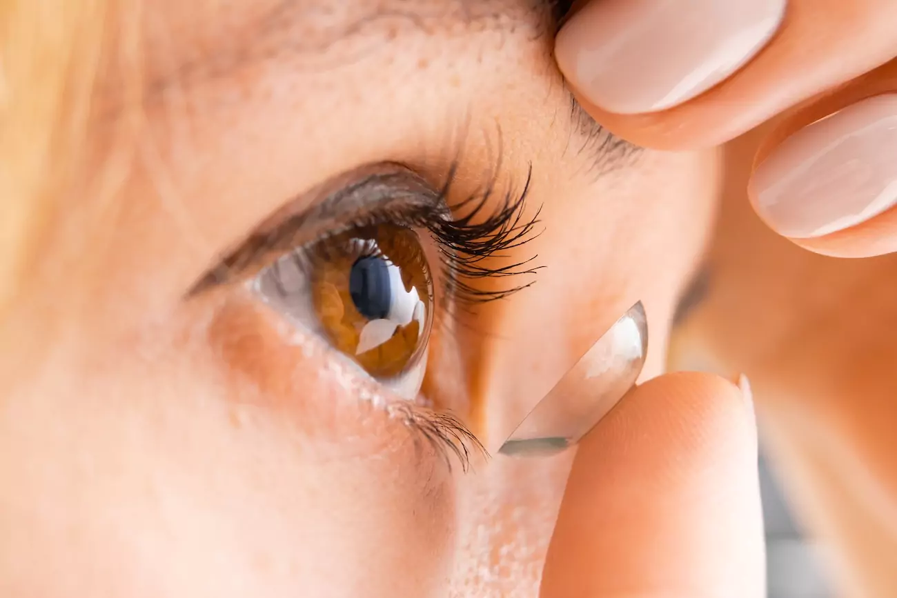 A women putting a contact lens in her eye.