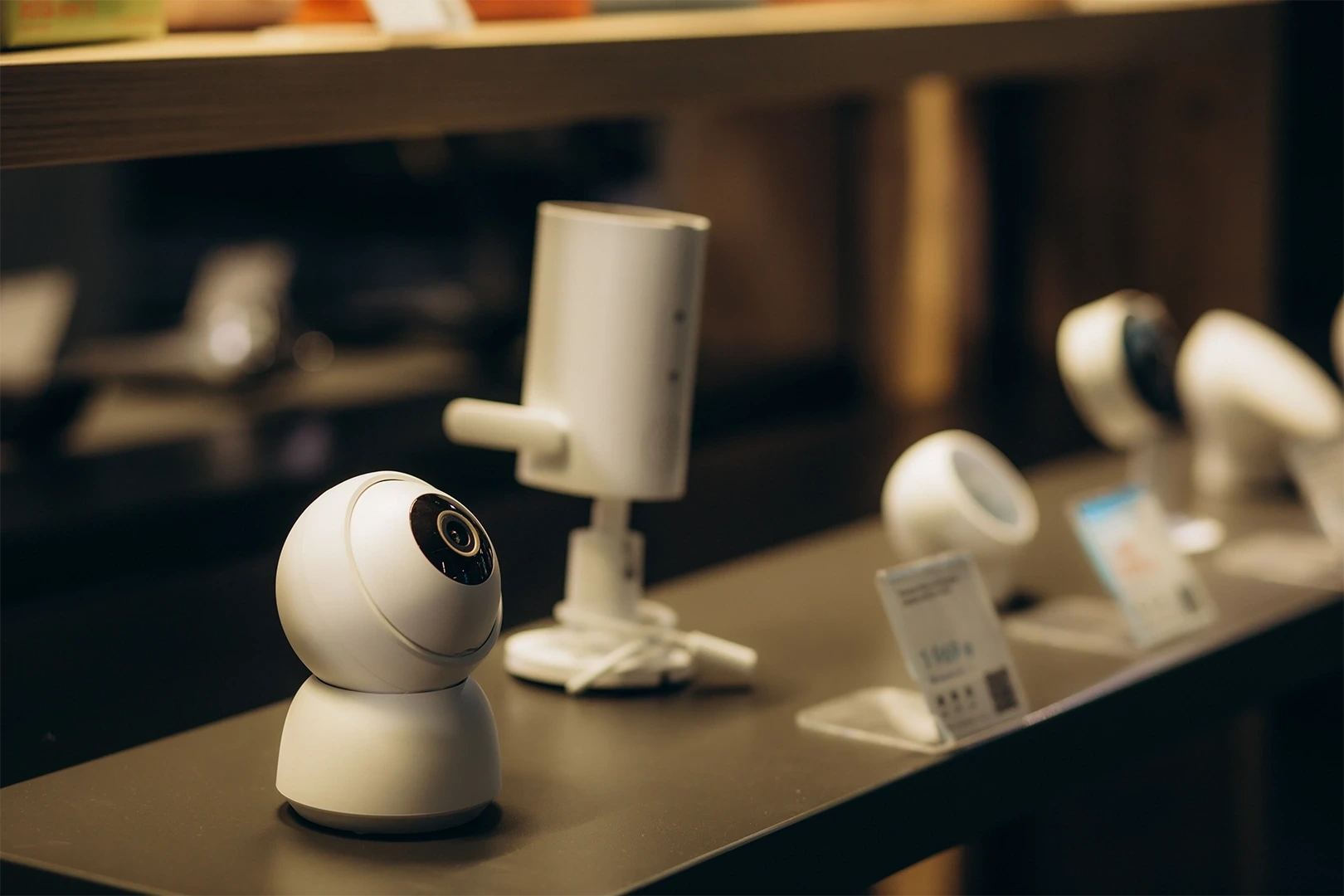 A display of modern IoT sensor devices, including smart surveillance cameras and monitoring units, showcased on a retail shelf. These devices are typically used in smart venue environments for real-time crowd management, security monitoring, and data collection.