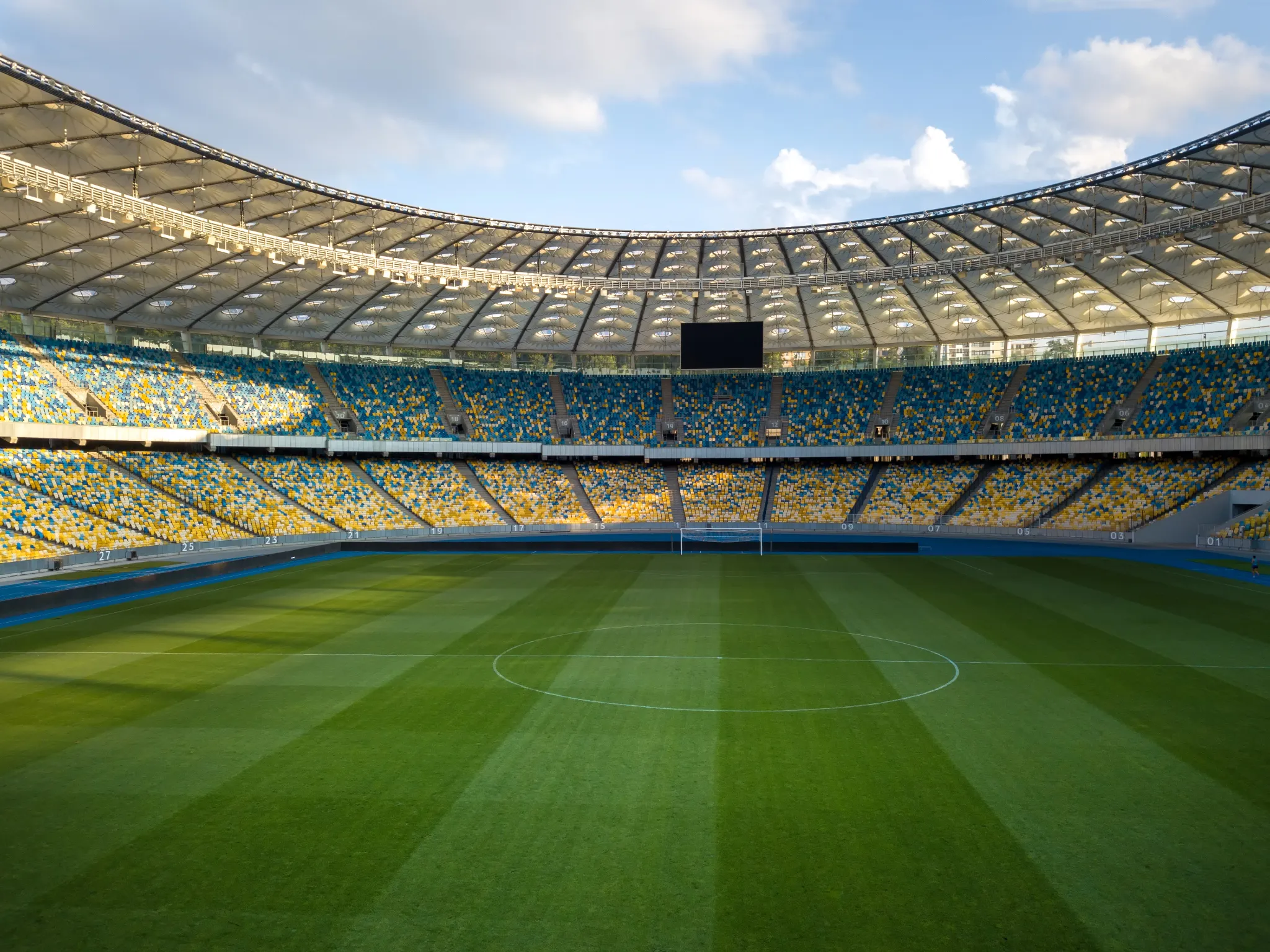 Empty football stadium with green grass field and blue-yellow stands, ideal for large-scale sports events and a key example of modern venue infrastructure in event management terms you should know.