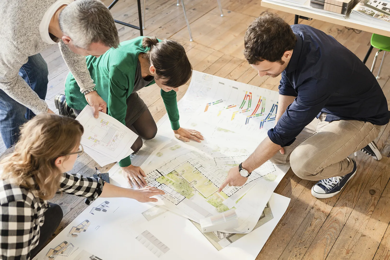Team of planners on the floor surrounded by large printed venue layouts and seating charts, representing the old-school, paper-based way of venue planning.