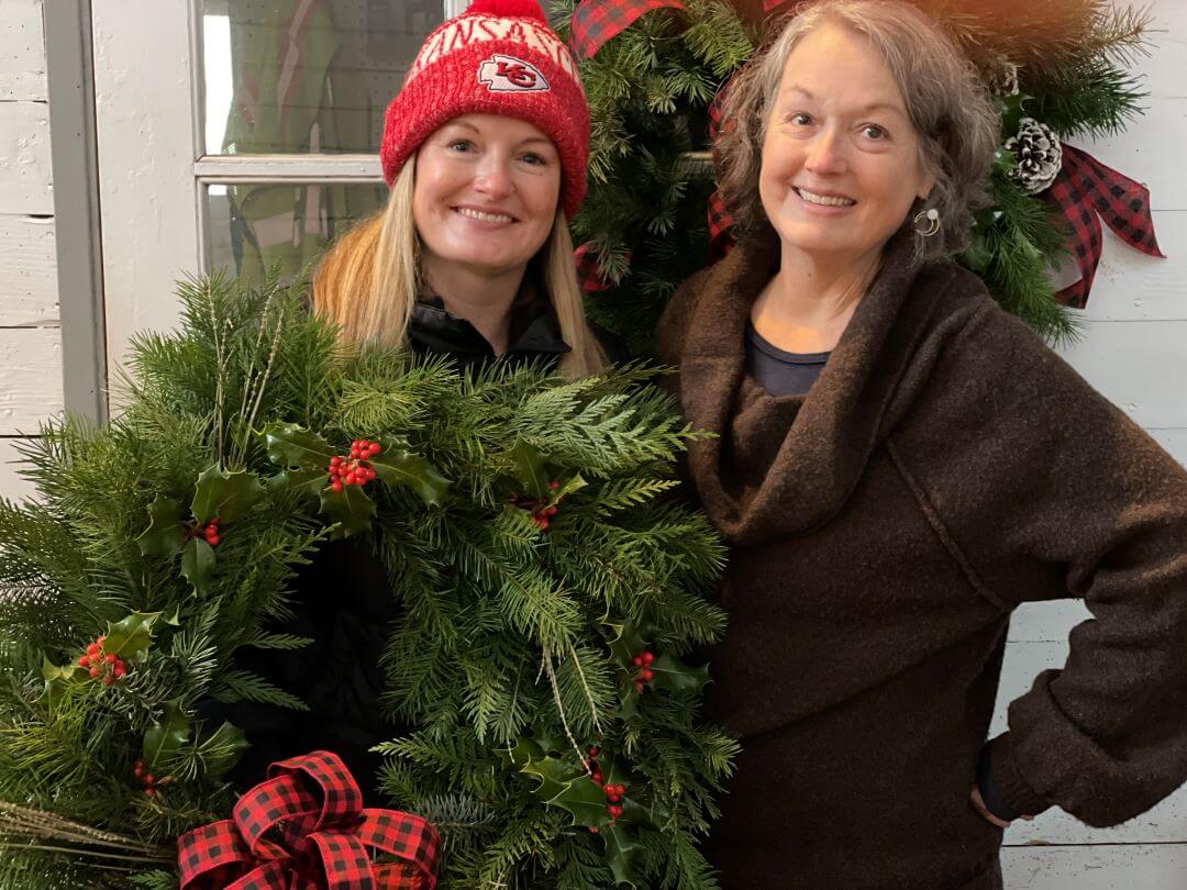 Holiday wreath workshop guests holding their wreath.