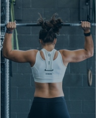 Back view of weight trainer lifting barbell.