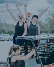 Cheering women atop an all-terrain vehicle.