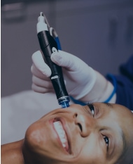 Smiling woman receiving skin treatment.