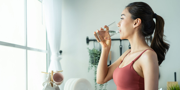 Woman drinking water to achieve weight loss goals.