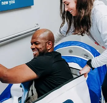 Nurse assisting man into the mild hyperbaric oxygen therapy chamber.