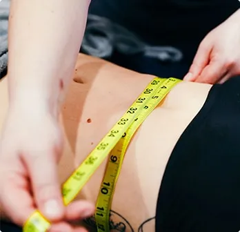 Yellow tape measure being used to measure a waist.