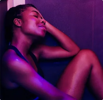 Woman receiving infra red sauna treatment inside infrared sauna.