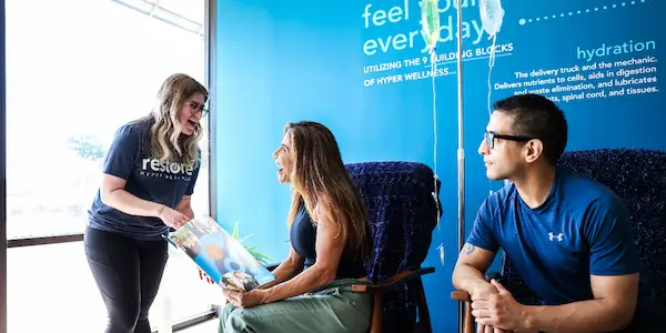 Image of a Restore Hyper Wellness rep showing customers an IV Drip Therapy menu.