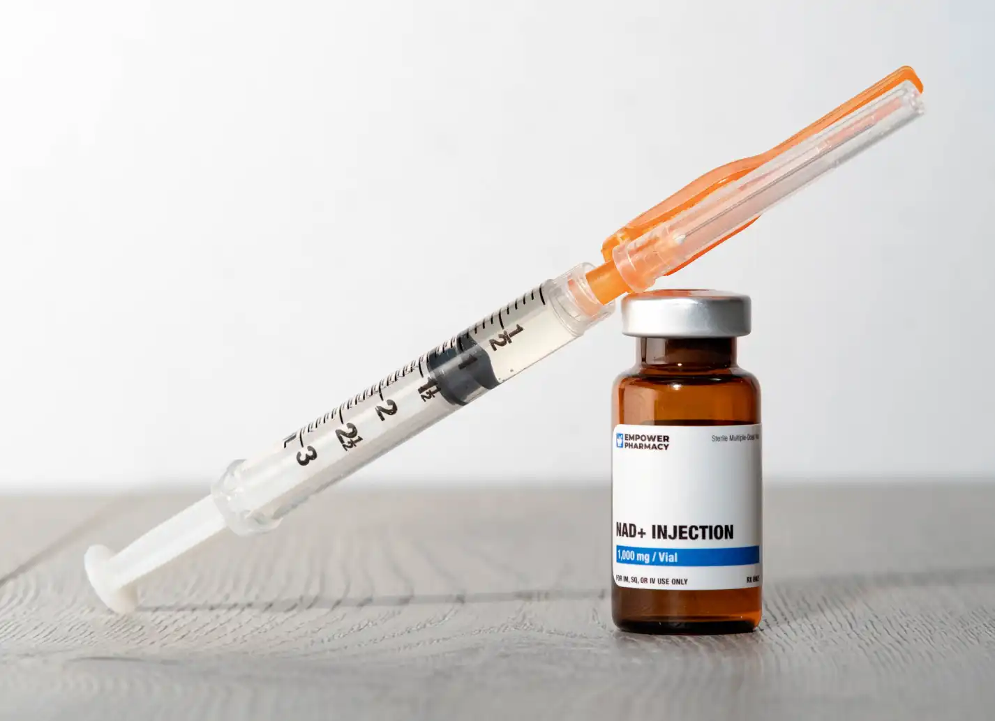 Syringe balances on an NAD+ Injection vial. 