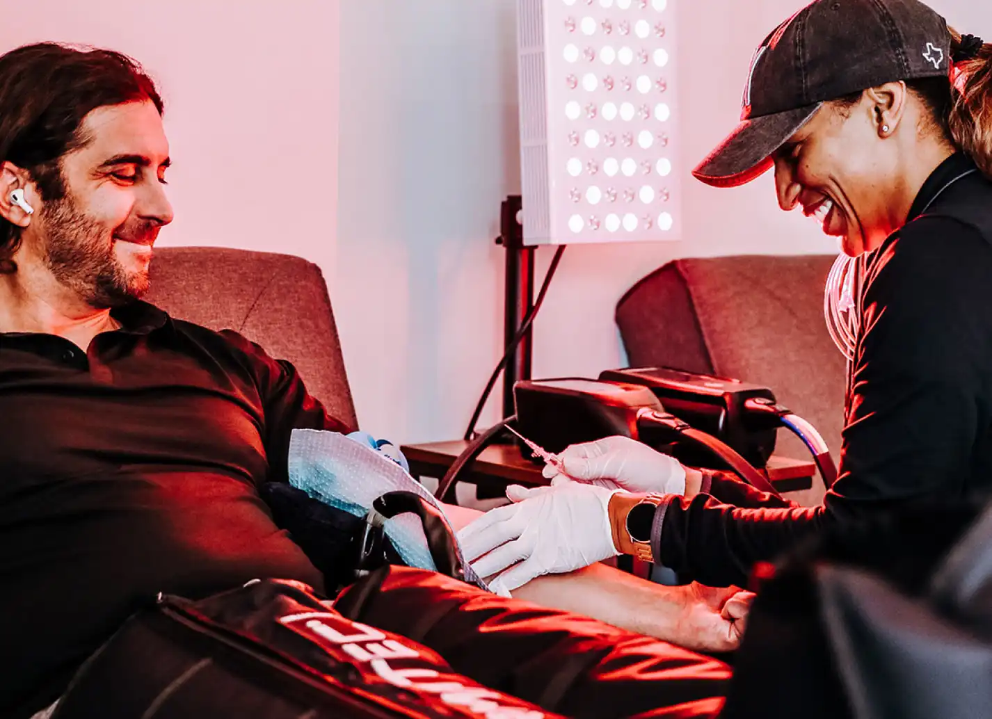 Hands shown putting in yellow vitamin to iv infusion bag with man in background.