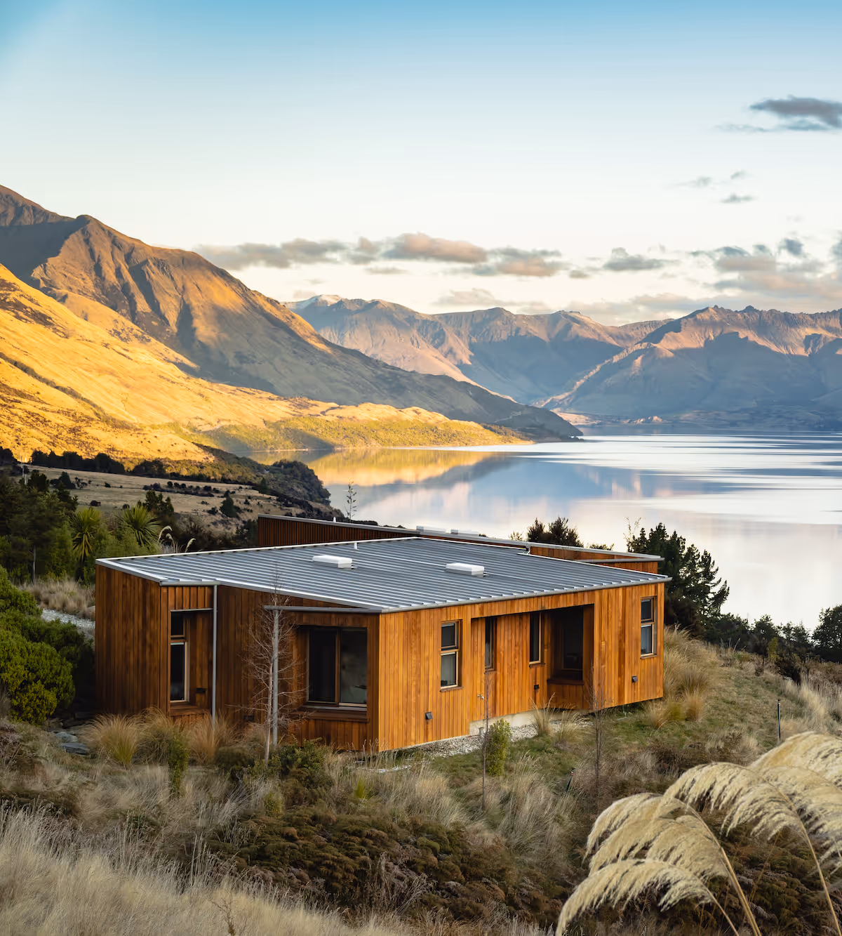 Eco-accommodation sitting on top of a lush green hillside with mountains and a lake in the background